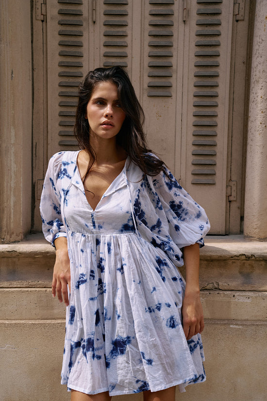 Kyra Mini Dress Deep Sea — back view against stone wall, deep sea shibori tie-dye cotton mini dress showing back neckline detail, European building facade | Daughters of India